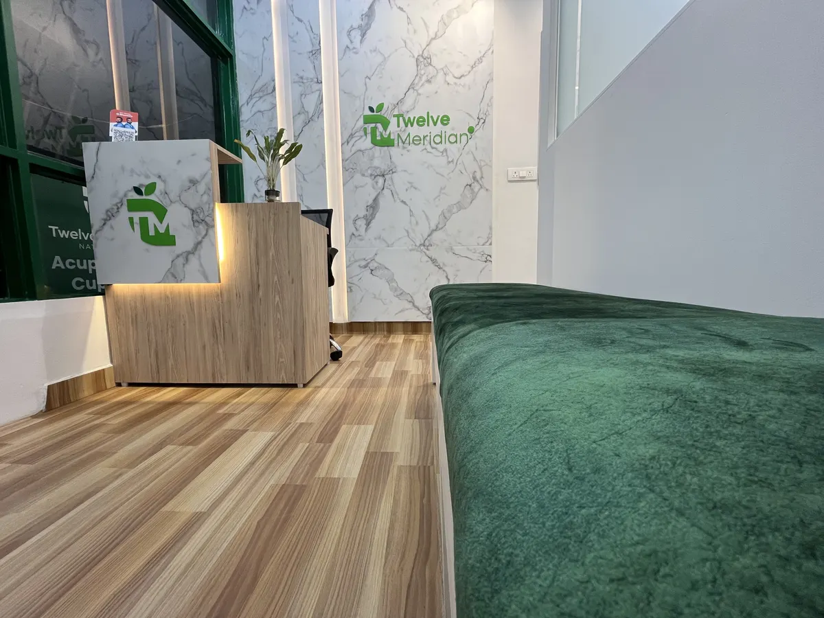Entrance and waiting area at Twelve Meridian, Sector 11, Noida: reception desk, marble wall with the Twelve Meridian logo and a green waiting bench